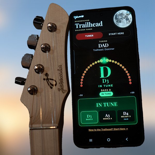 A Trailhead headstock beside a phone showing the Trailhead Companion tuner in tune